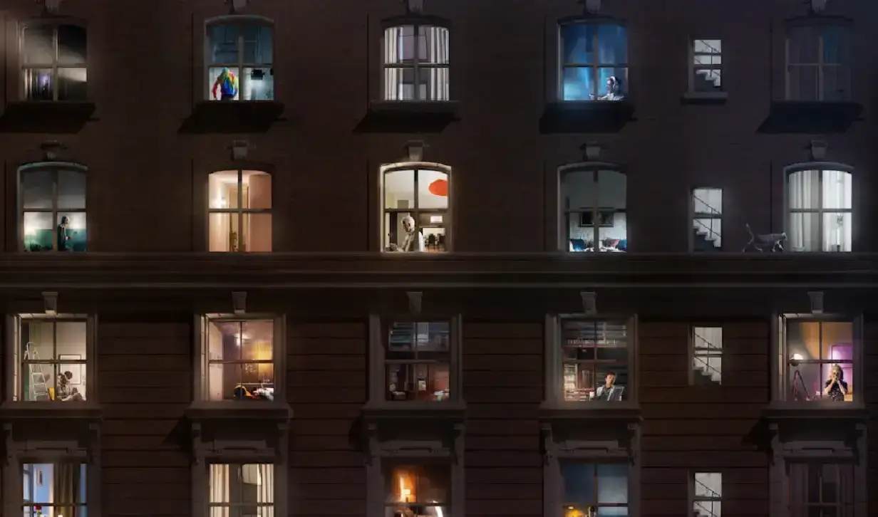 Nighttime view of the Arconia apartment building with illuminated windows showing glimpses of residents' lives.